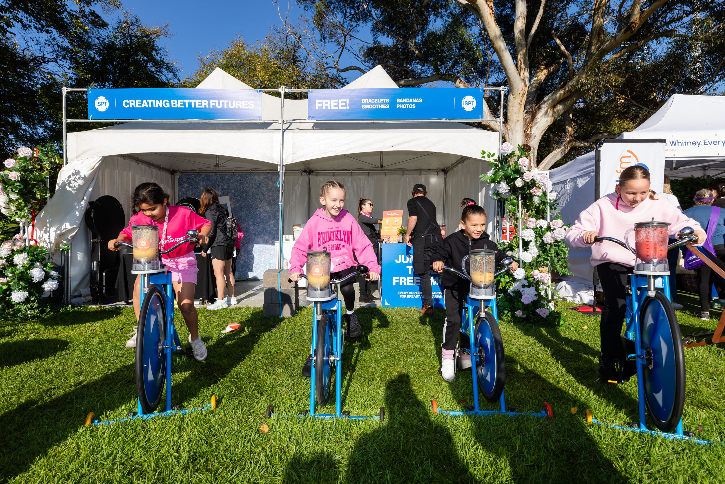 Kids cycling on exercise bikes in front of ISPT tent